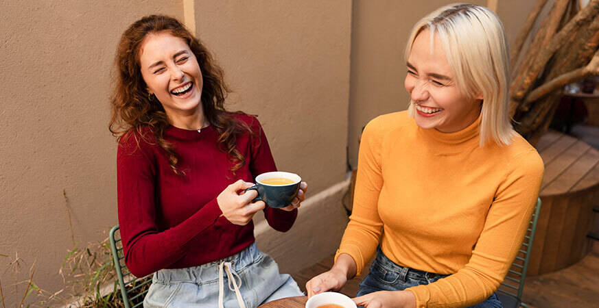 two women sitting down drinking tea and laughing