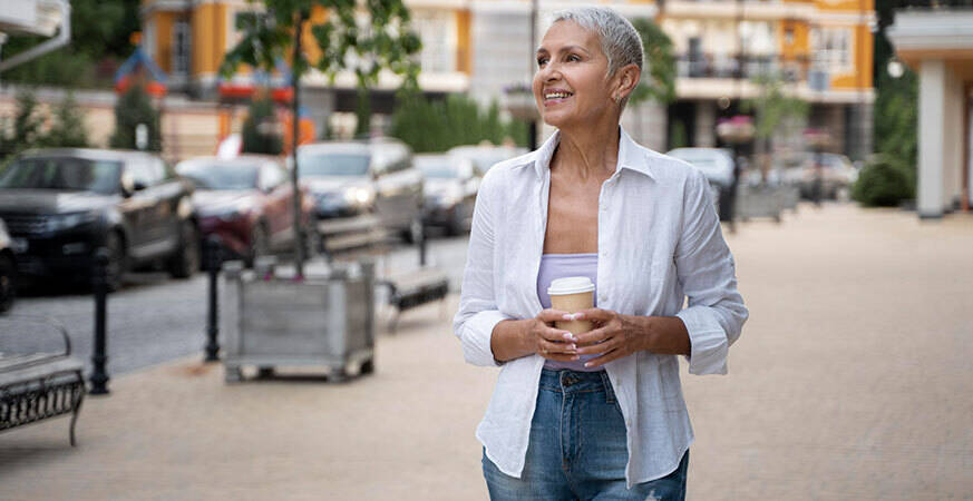 woman holding a coffee cup walking through the city